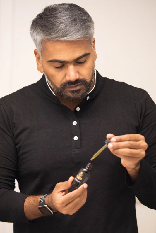 A man applying Oyu Cosmetics Growth Beard Oil, enjoying a moment of self-care and grooming.